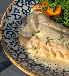 Mesa posta de Páscoa com louças elegantes e prato de bacalhau com natas ao centro